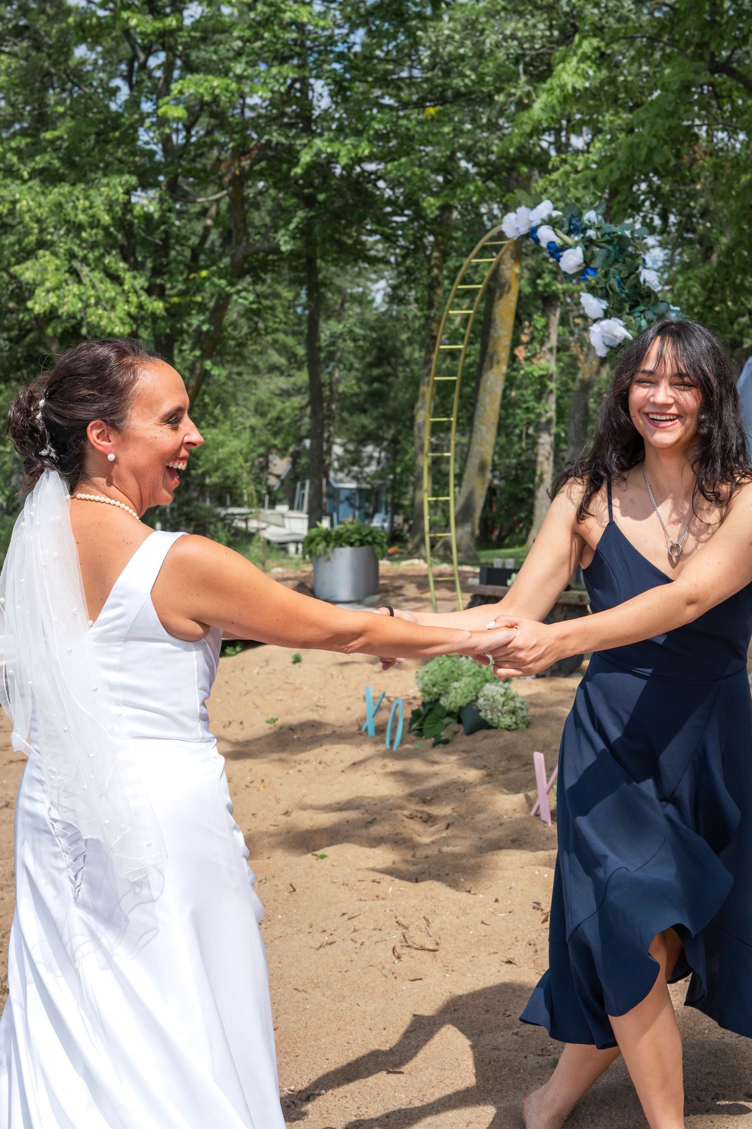 Mom and daughter share a joyful dance moment in a wooded outdoor setting.