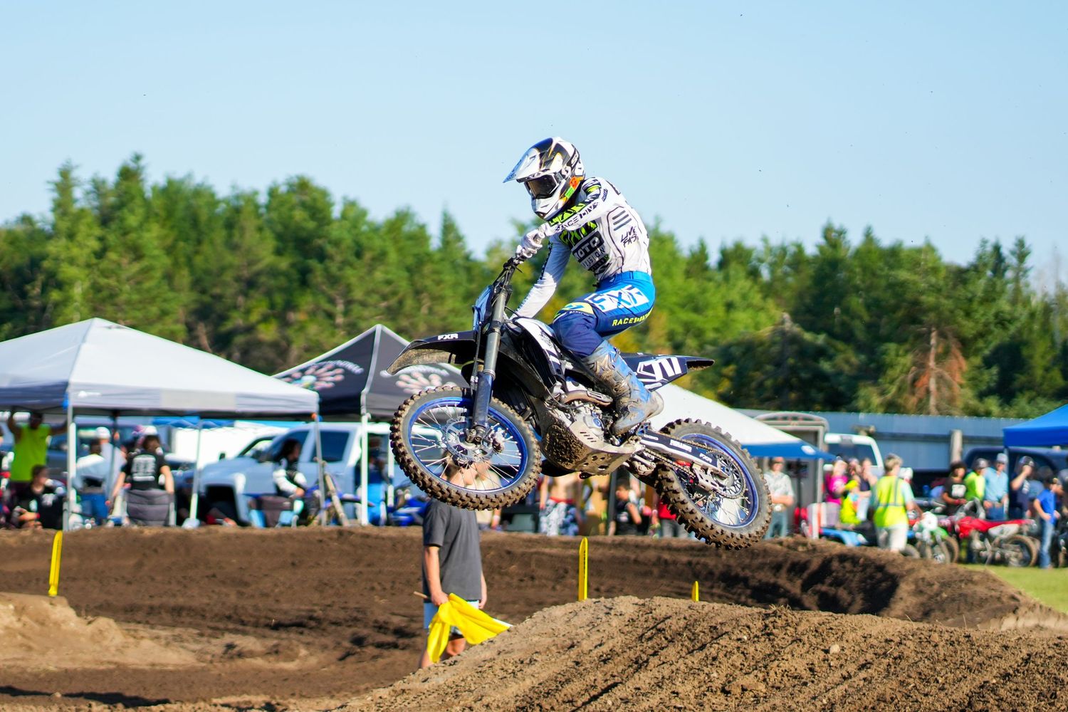 Motocross riders soaring through the air during a competitive dirt track race.