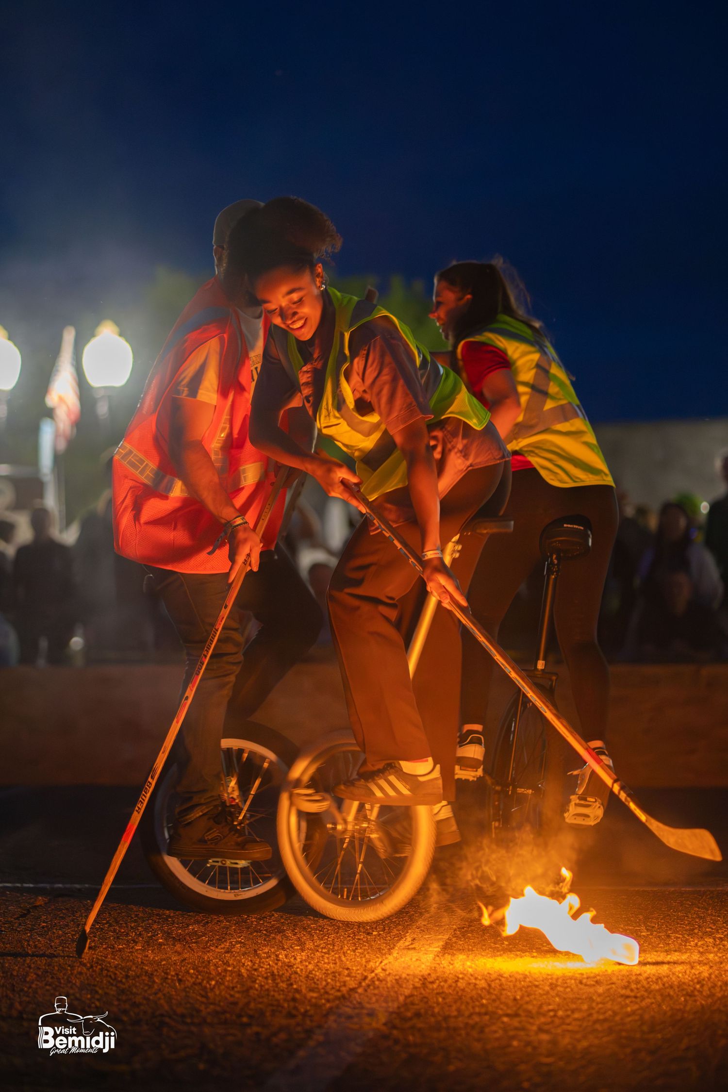 Fire performance with unicycles creating dramatic orange glow effects at night.