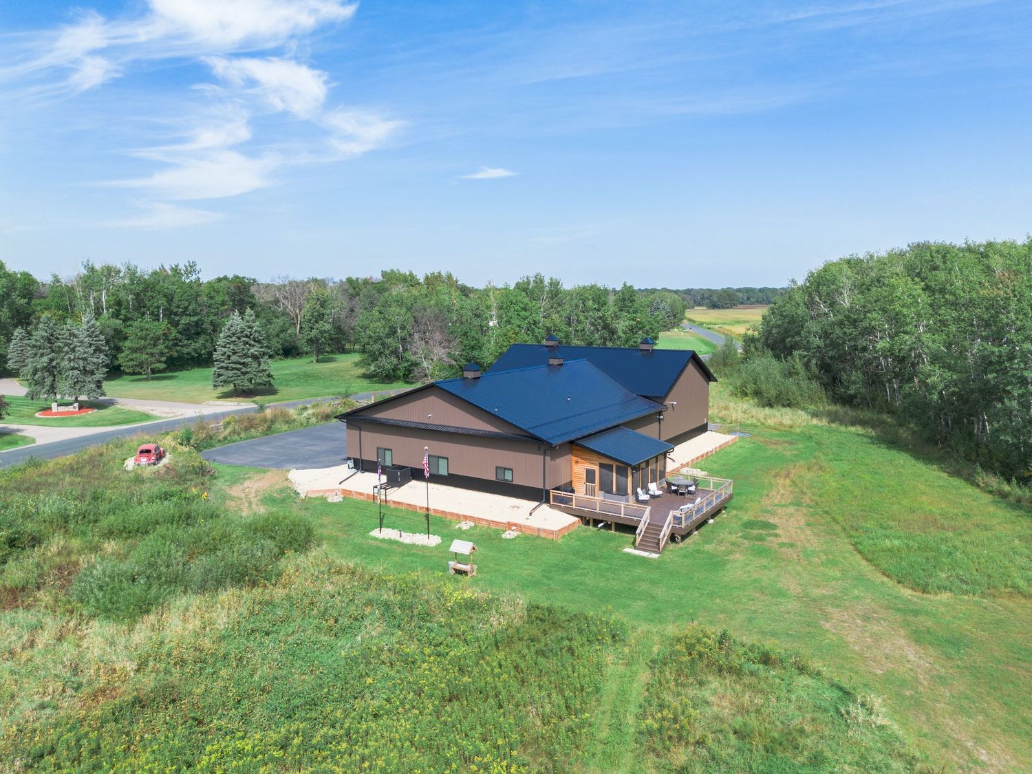 Aerial view of a large property with brown buildings nestled among green fields and trees.