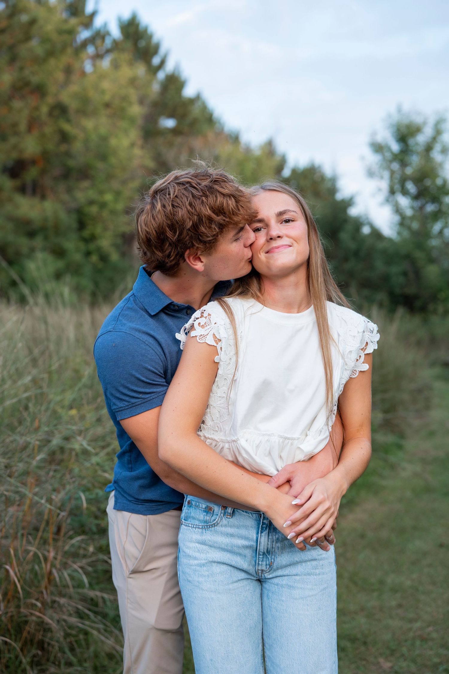 A couple share moments while standing together in a grassy field.