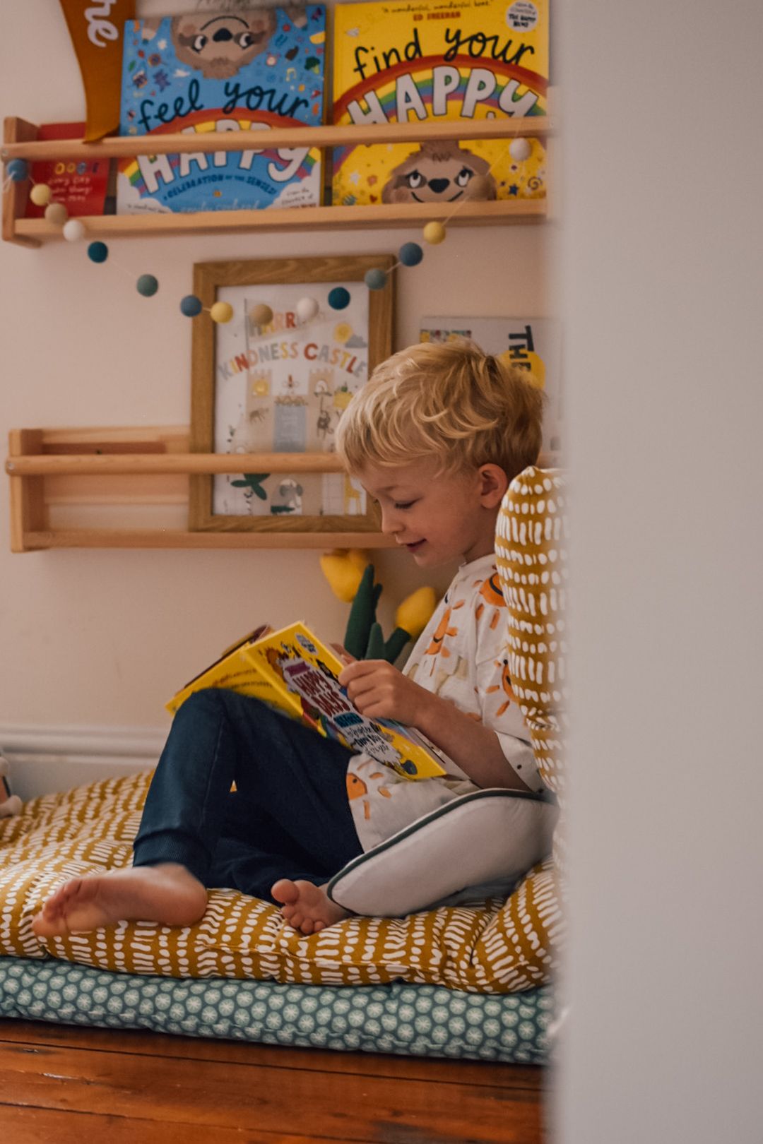 Boy reading a book in front of book case.
