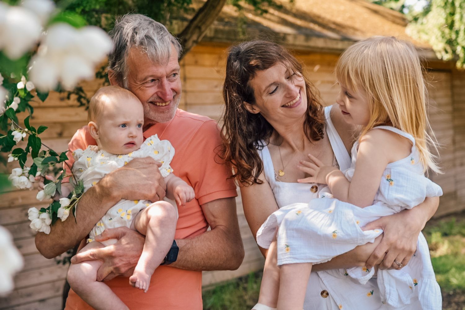 Grandfather holding a baby next to Mother holding a Girl