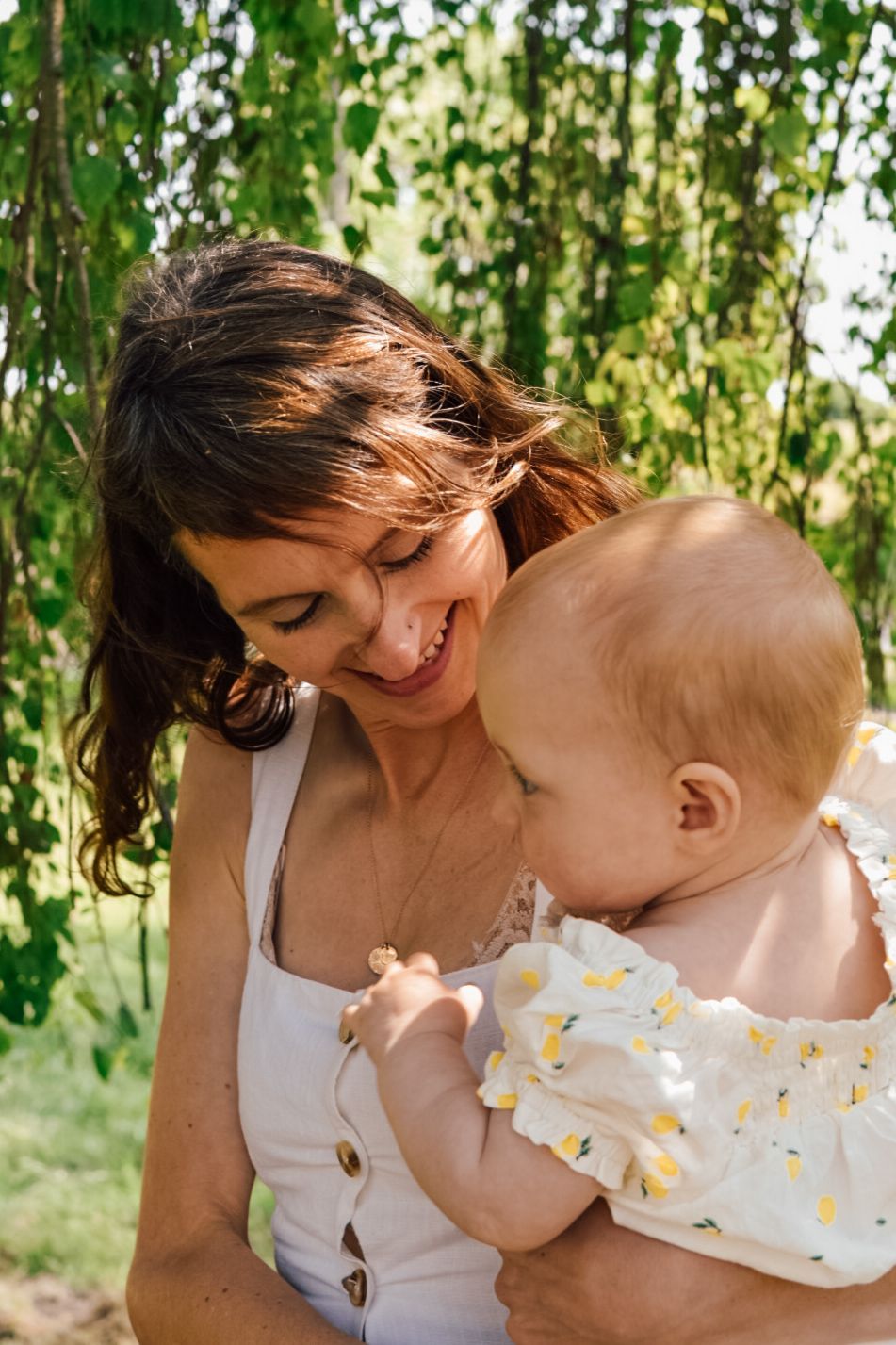 Mother holding a baby with green trees in the background