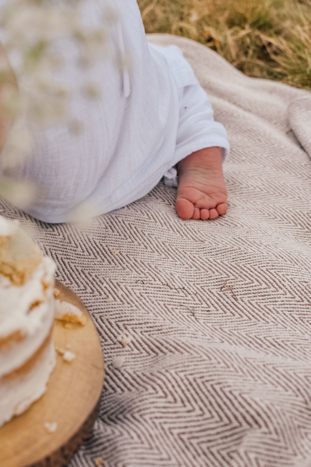 Baby's foot and cake on top of a blanket.