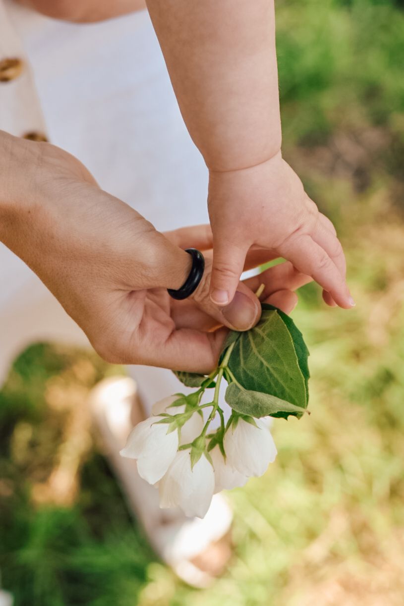 Hands of a mother and baby holding blossom in the garden