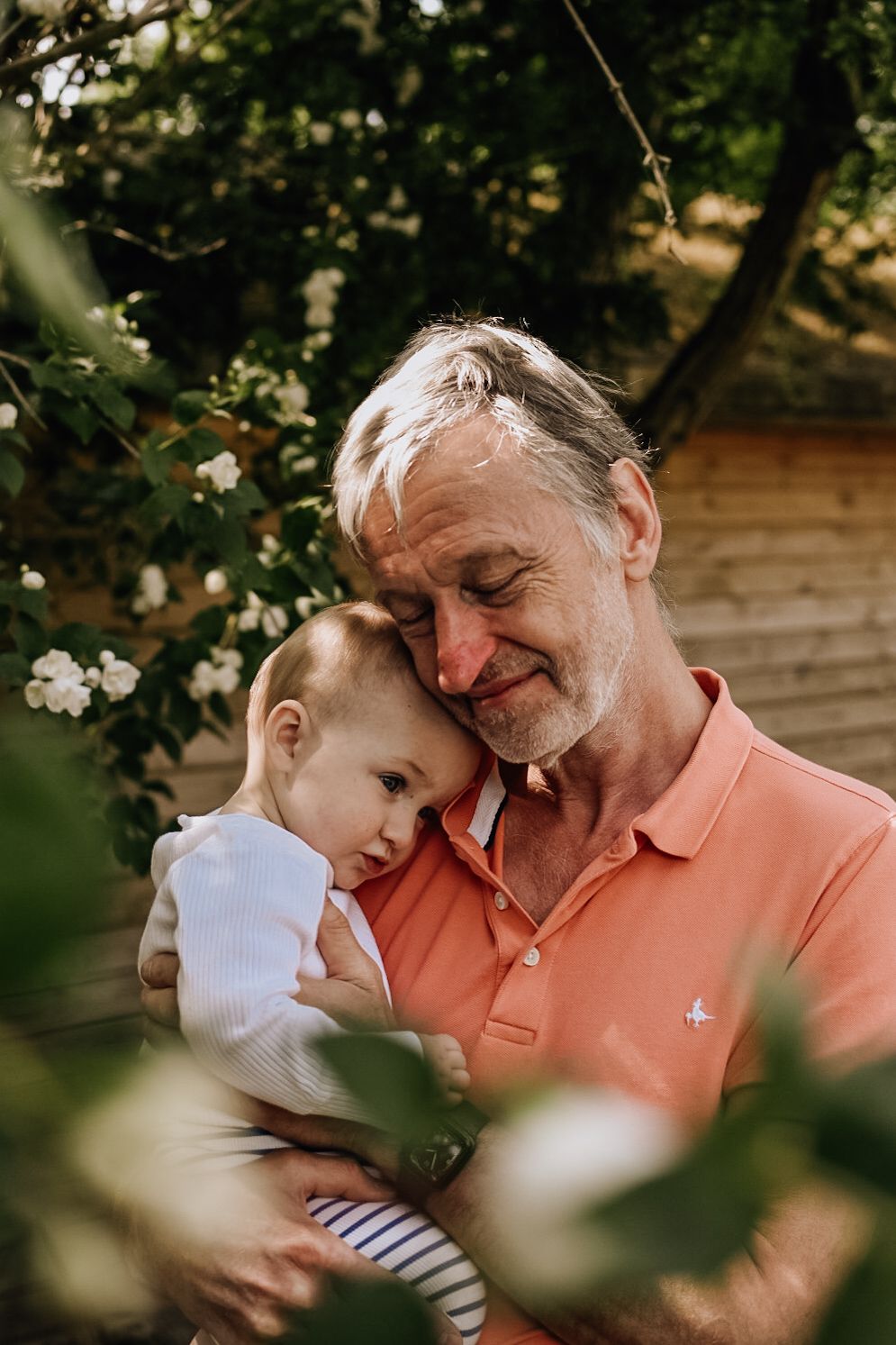Grandfather cuddles with baby in the garden