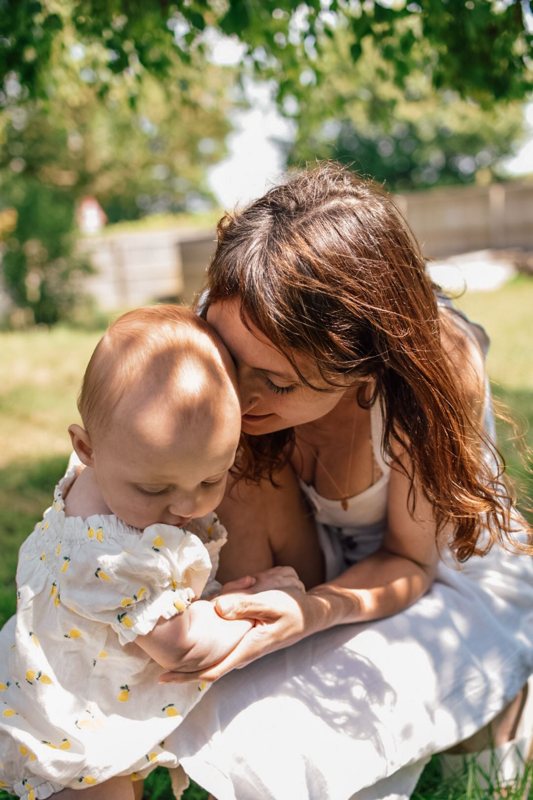 Mother and Baby sat on blanket cuddling in a garden
