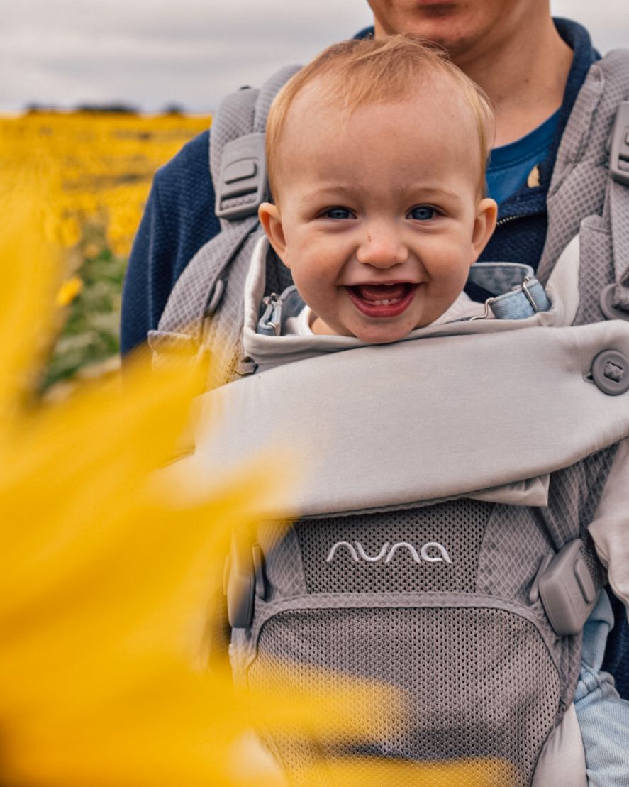 Baby in carrier on mans chest with sunflower petals in foreground