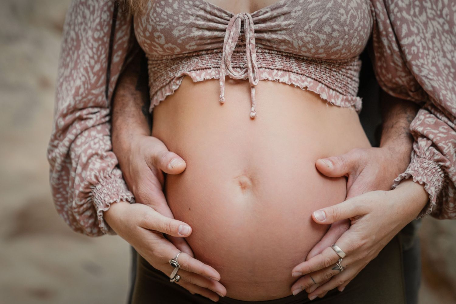 Maternity photography with woman's baby bump and husband caressing her belly