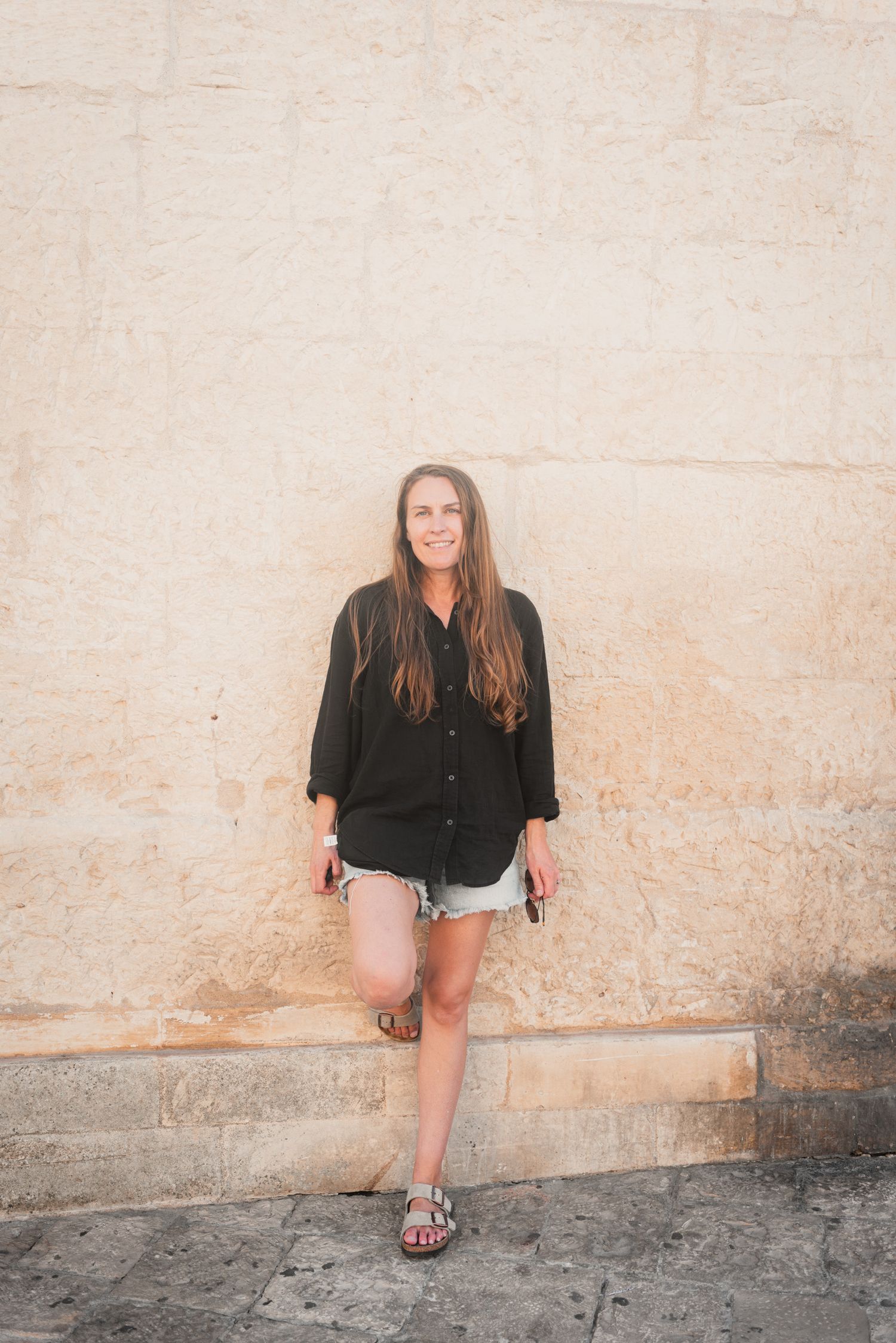 photographer posing against a stone wall