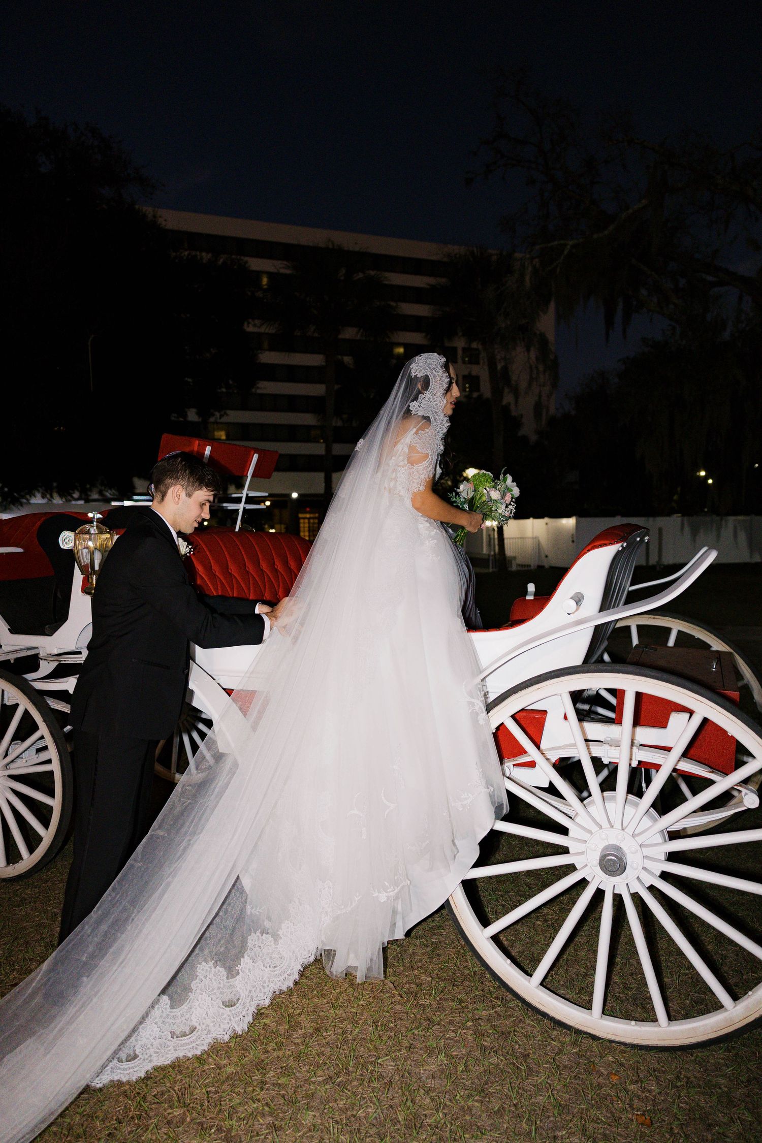 White horse-drawn carriage with flowing bridal gown details at night.