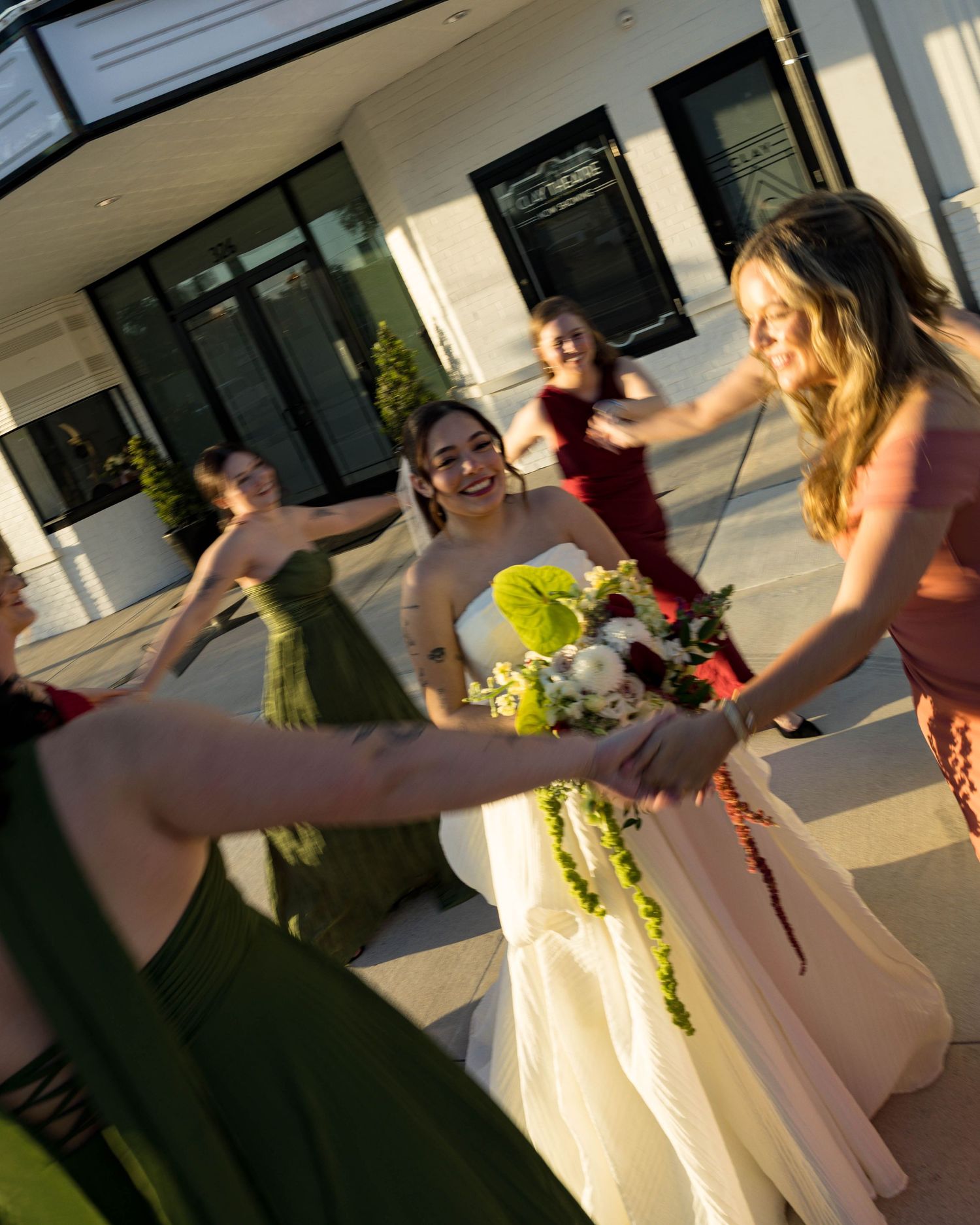 Candid moment of a wedding party celebrating outside a theater entrance.