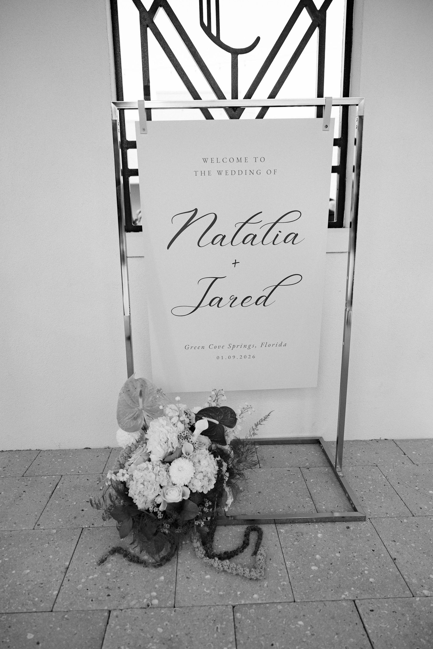 Wedding welcome sign for Natalia and Jared with floral arrangement at the base.