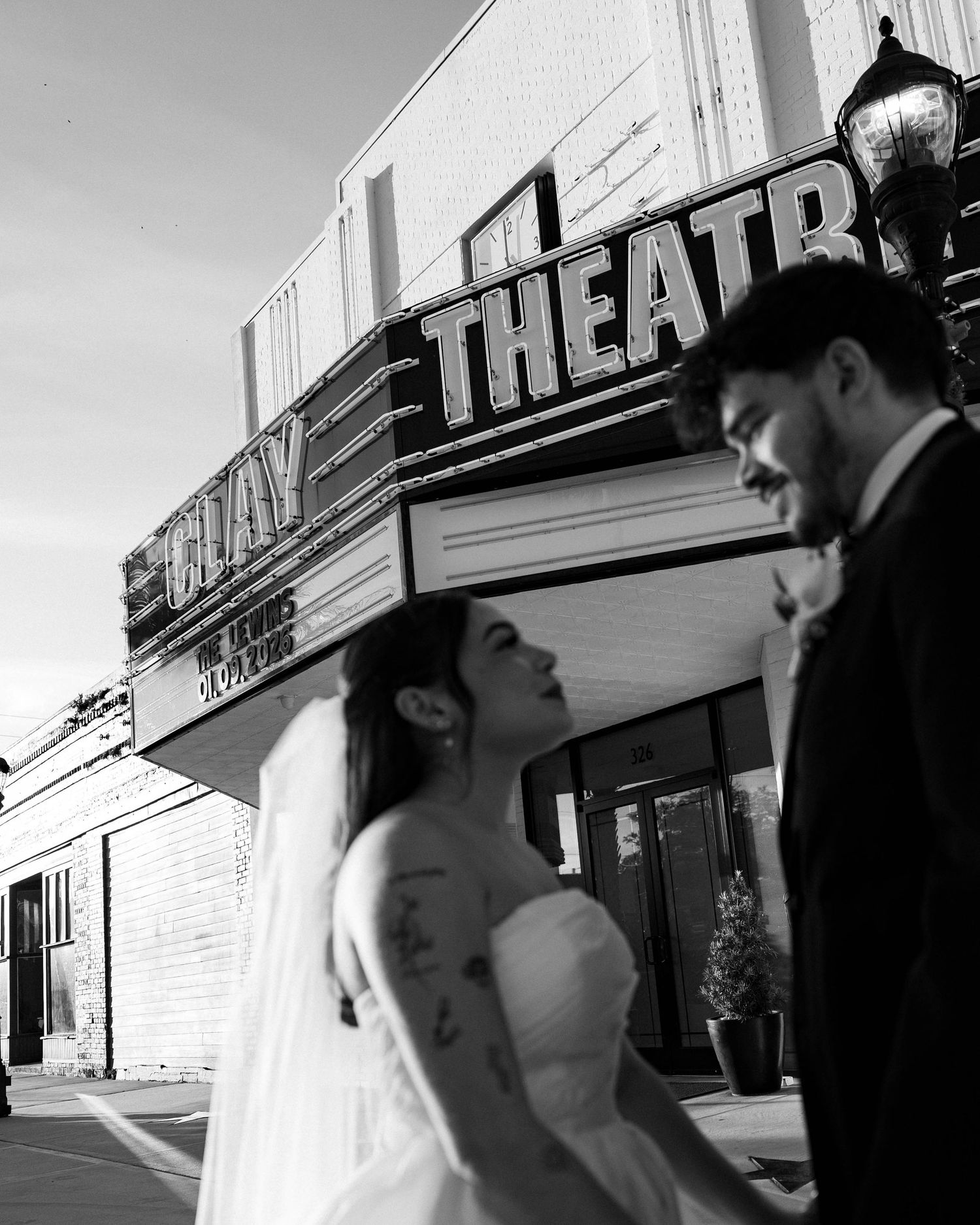 A romantic black and white wedding photo captured in front of a vintage theatre sign.