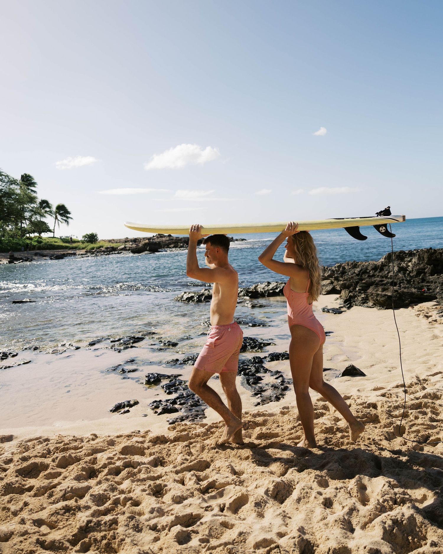 Series of shots showing surfers walking along tropical beach with surfboard.