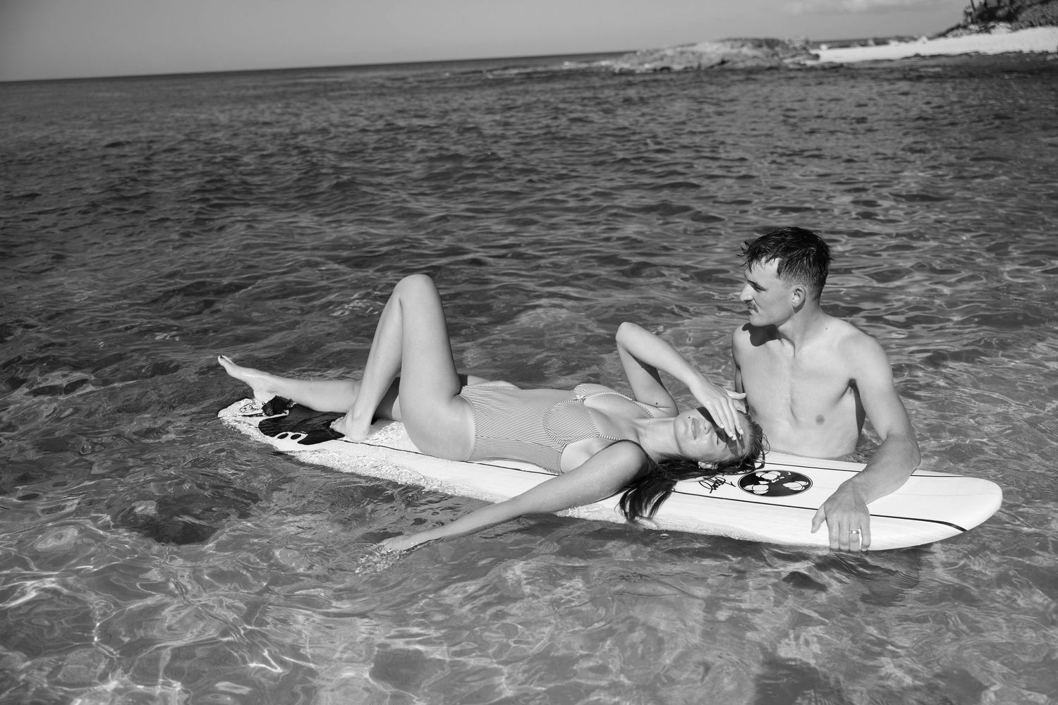 Monochrome image of people relaxing on surfboards in calm ocean waters.