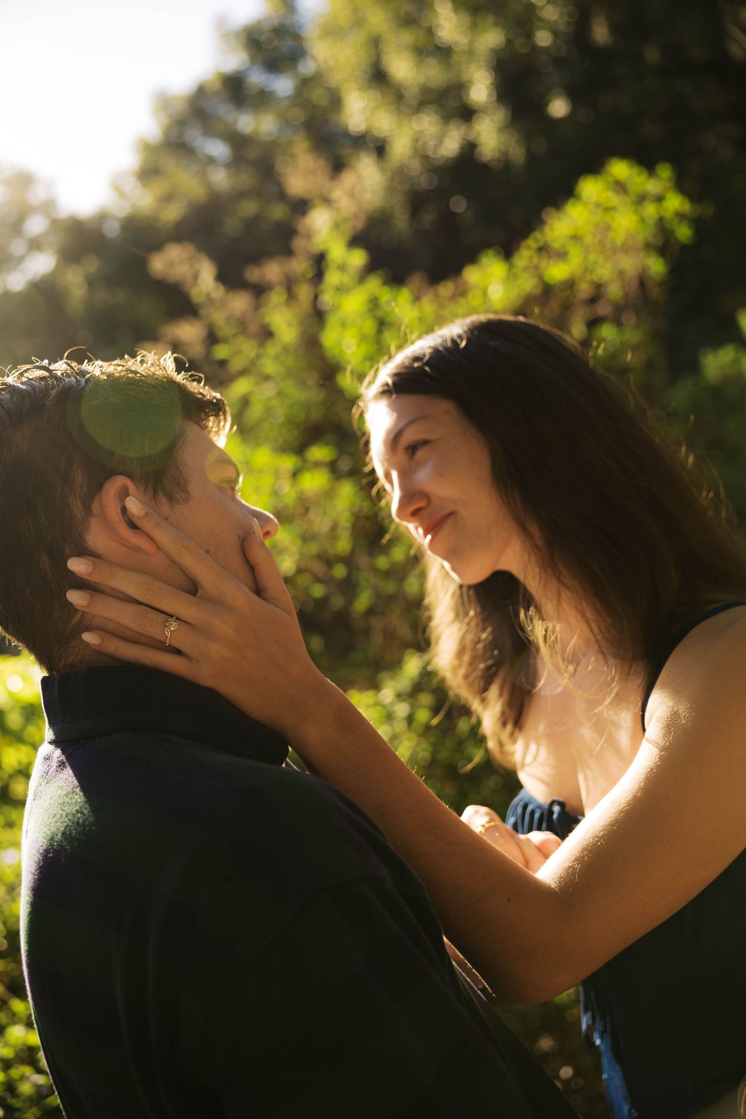 Sunlit wedding couple shares an intimate moment in a garden setting.