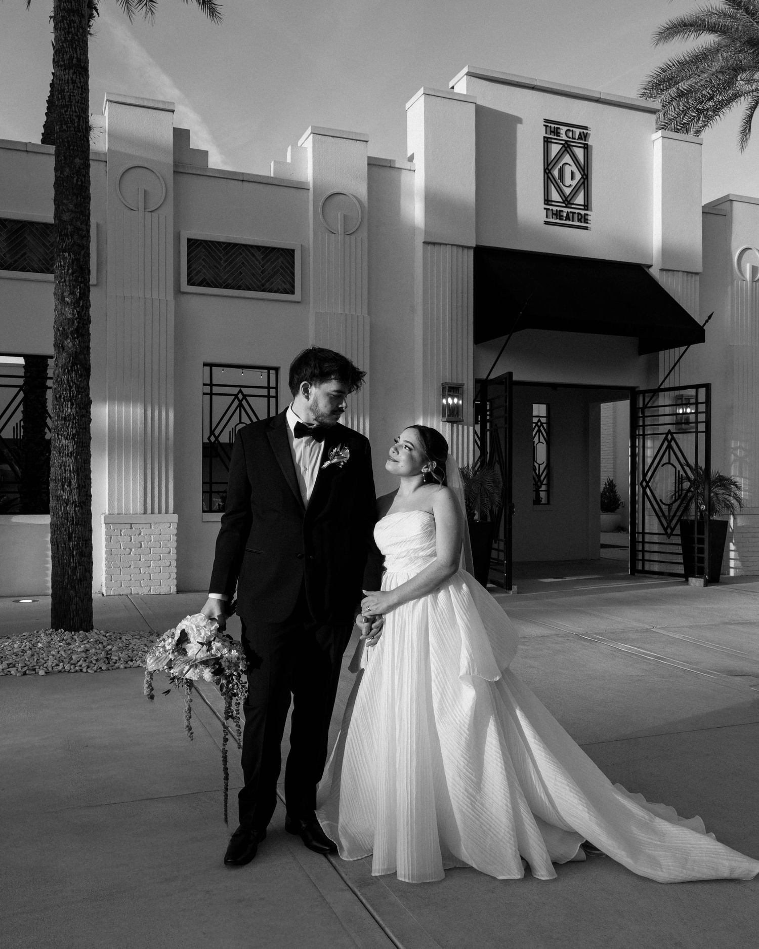 Black and white wedding portraits outside modern building with columns.