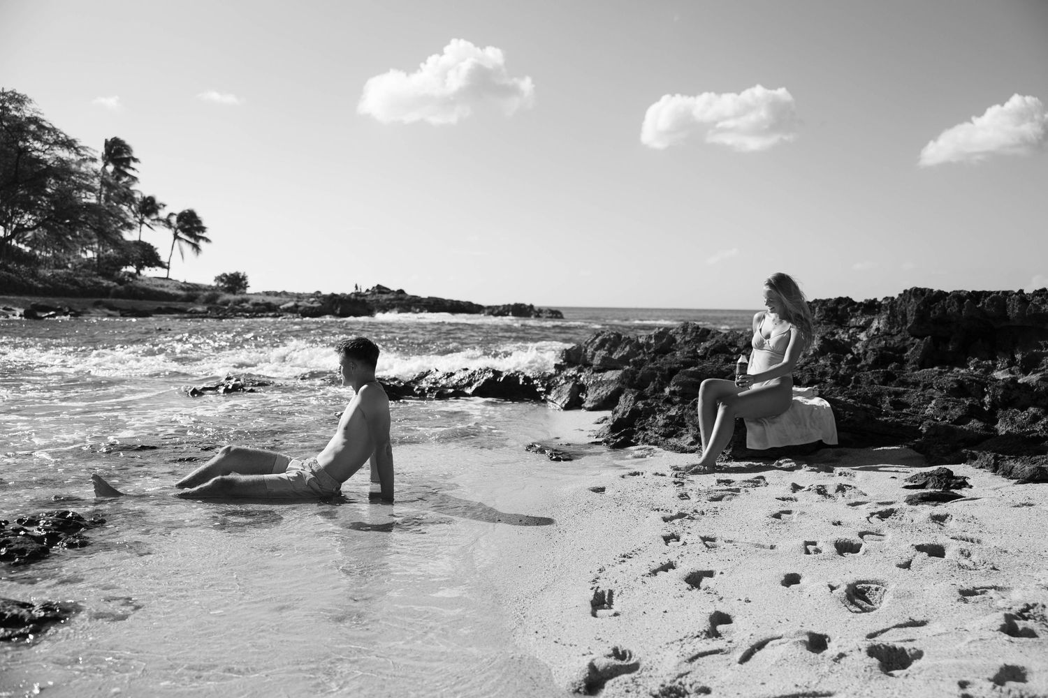 Black and white beach scene with distant figures relaxing on sandy shore.