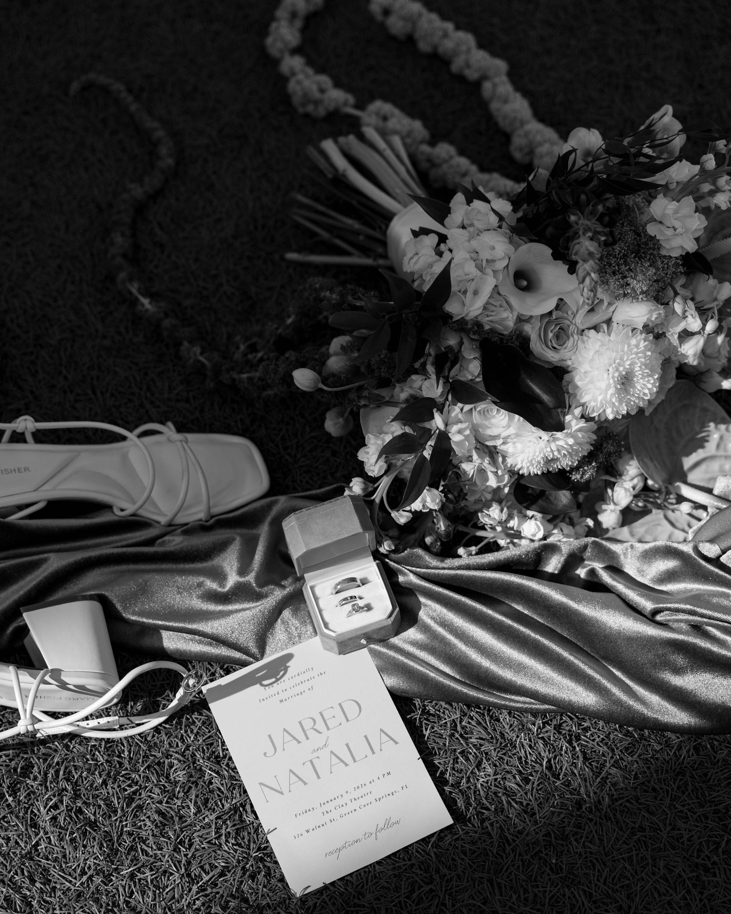 Dramatic black and white photo of wedding decor with floral arrangements and name cards.