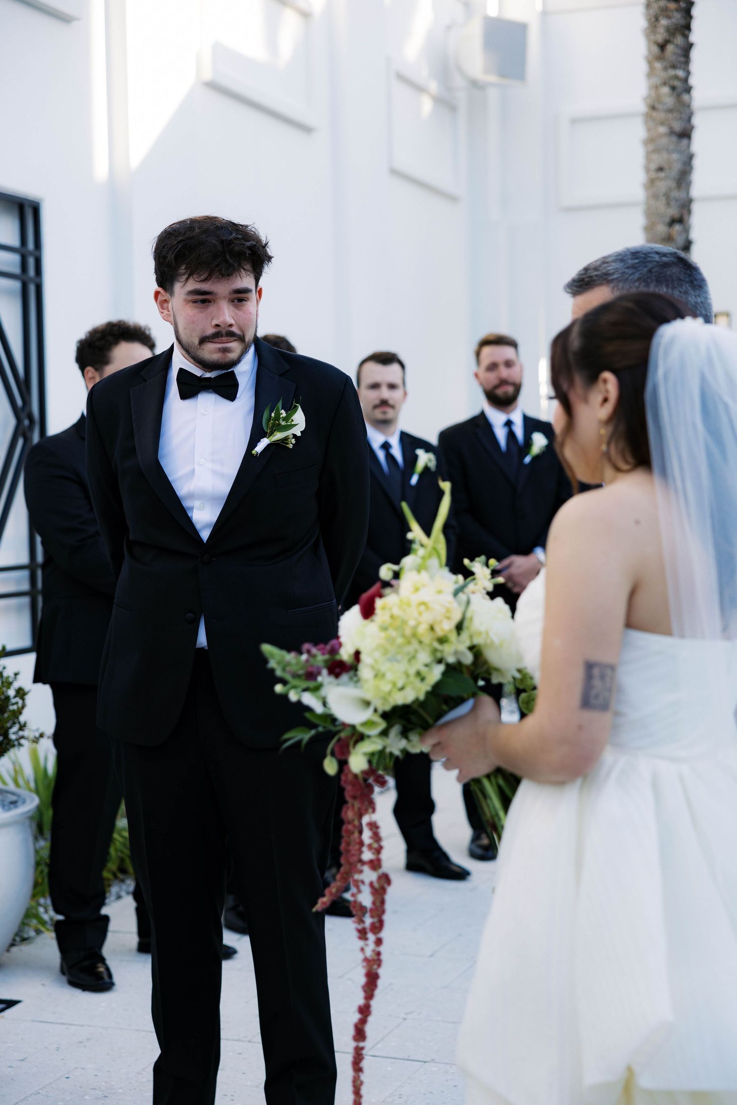 A wedding ceremony moment with the couple exchanging vows in front of an elegant white building.