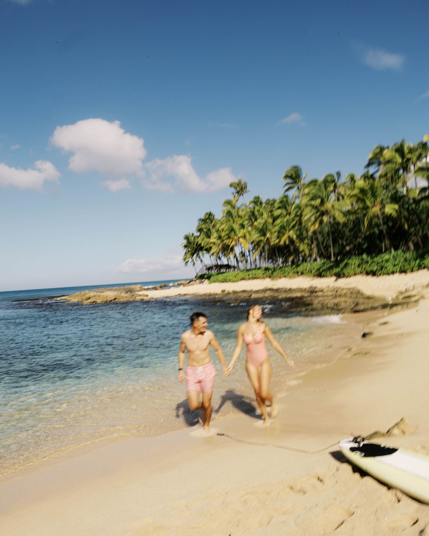 Scenic beach landscape with palm trees and people walking along the sandy shoreline.