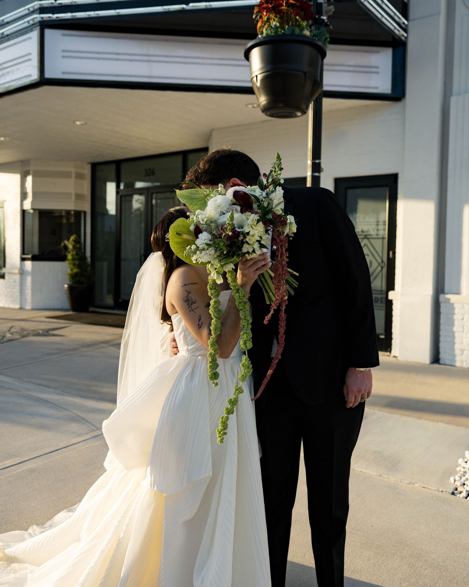 Elegant wedding portrait with flowing dress and bouquet outside historic theater entrance.