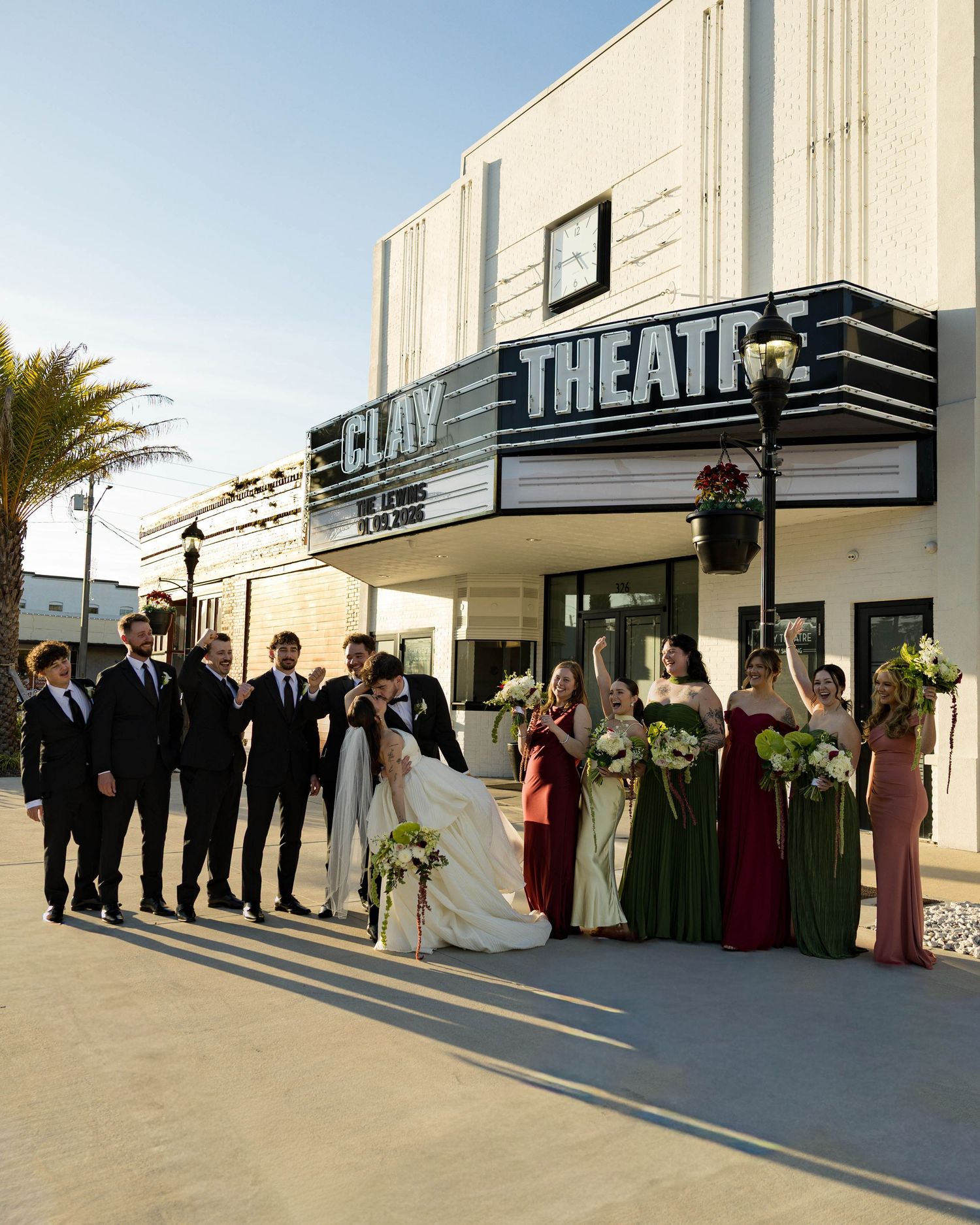 Sunset wedding party photo session outside vintage theatre with classic marquee signage.