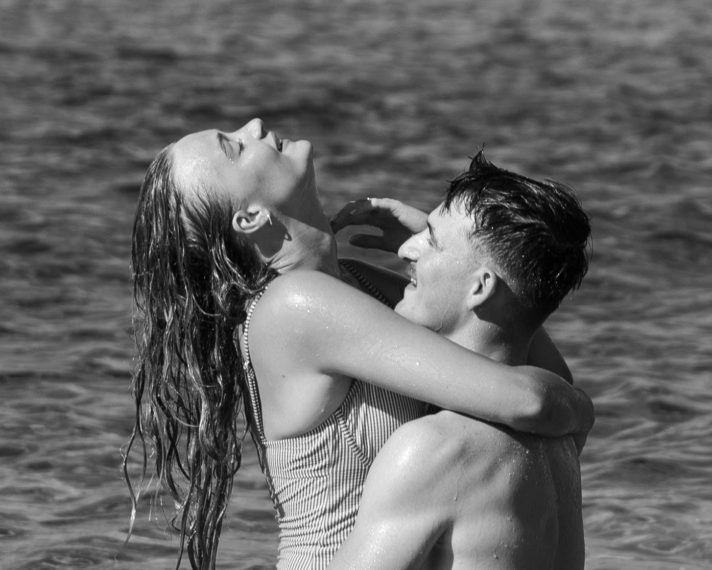 Romantic black and white portrait of couple in ocean water.