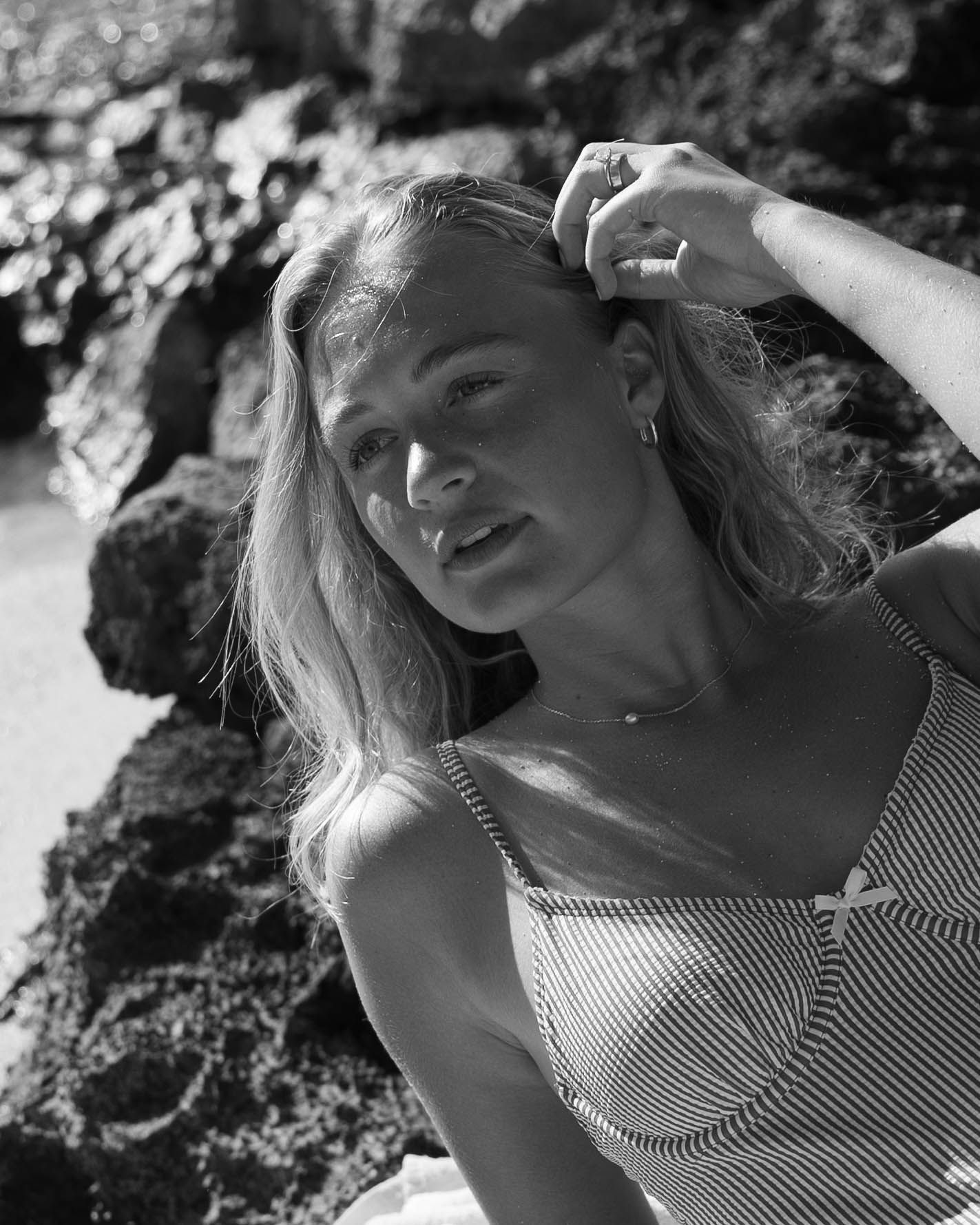 Close up black and white portraits showing someone in a striped swimsuit at the beach.