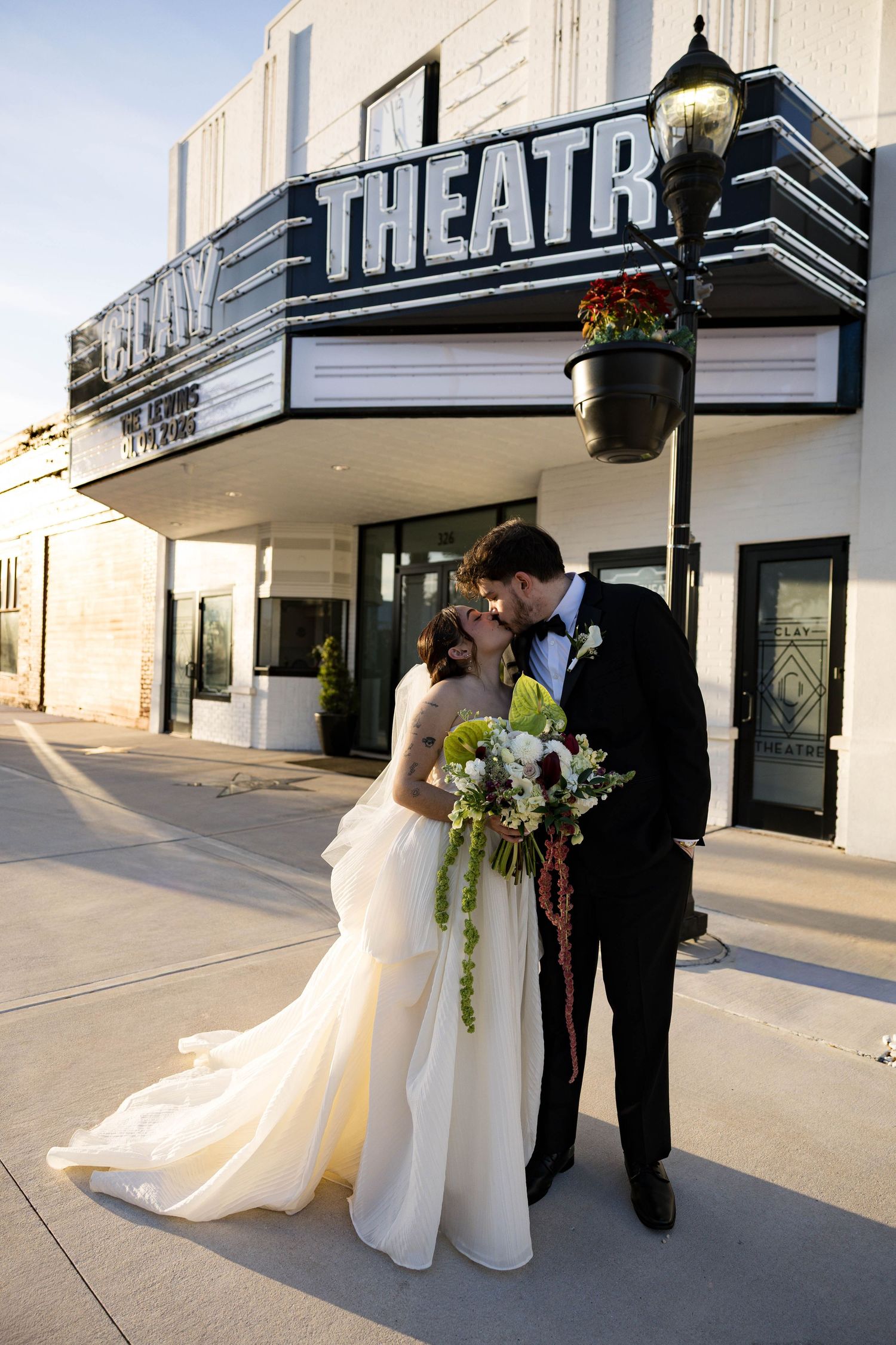 Romantic wedding portrait outside an art deco theater with vintage signage.