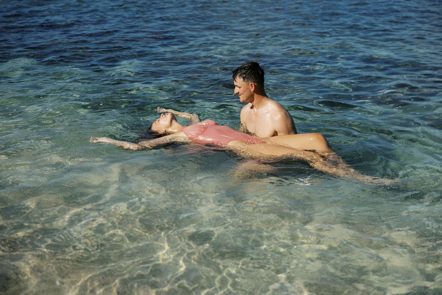 People enjoying a swim in clear tropical waters near a beach.
