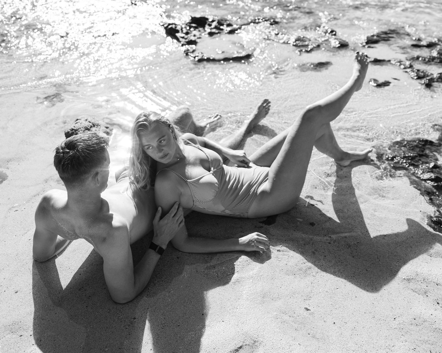 Monochrome series showing beach poses on sandy shore with waves in background.