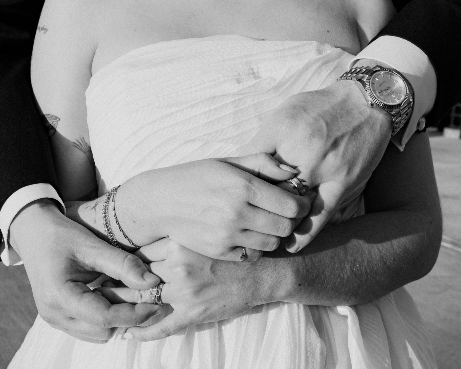 Close-up black and white photo of hands holding a baby wrapped in white fabric.