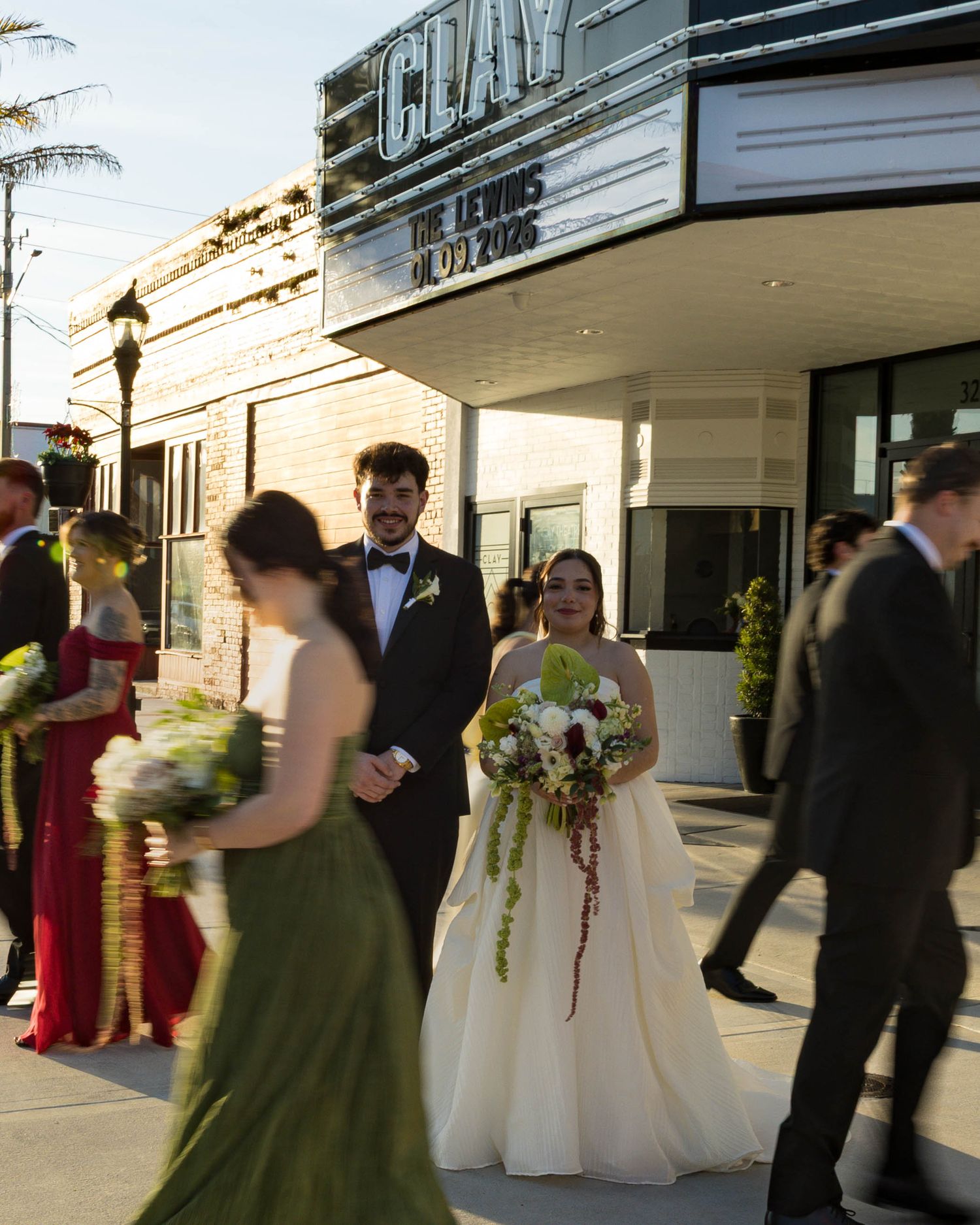 Wedding party lined up outside historic theater entrance with bridesmaids in alternating colors.