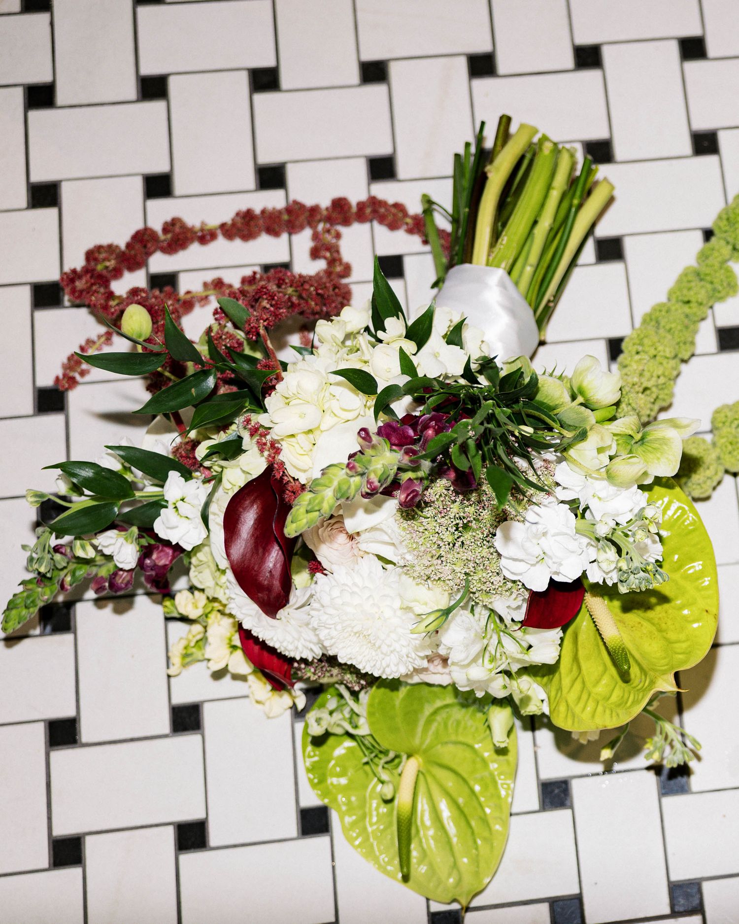 Modern floral centerpiece displayed on geometric black and white tiled surface with name cards.