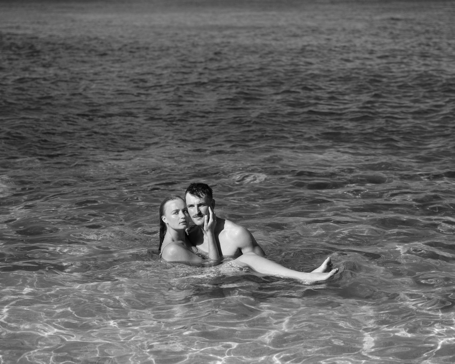 Black and white photo of swimmers floating in ocean waves.