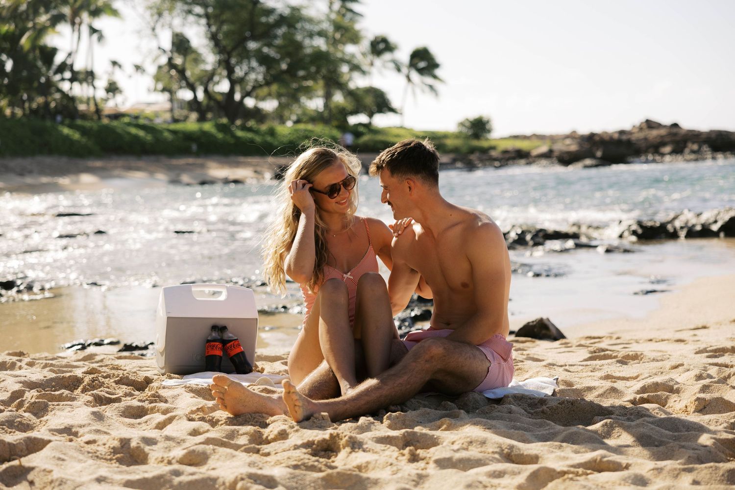 Couple relaxing together on a sunny tropical beach with ocean views.