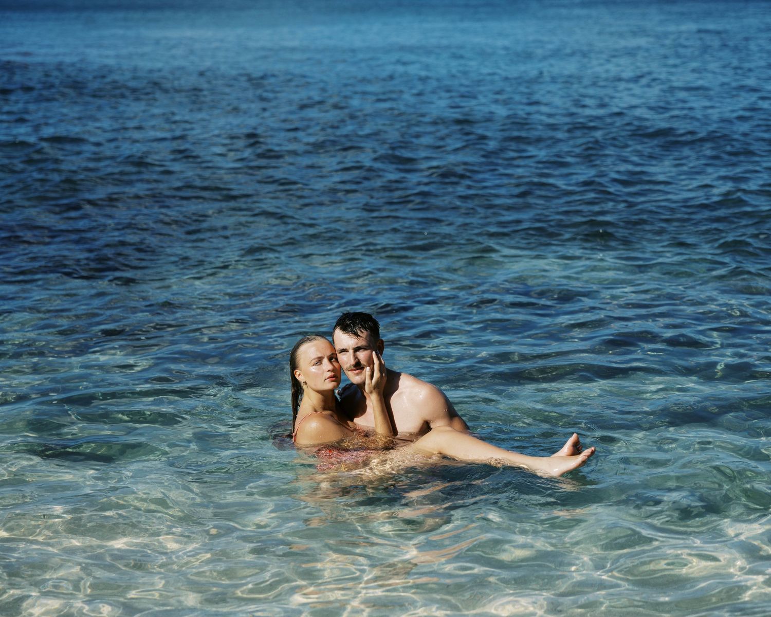 Two swimmers floating in tranquil blue ocean waters.