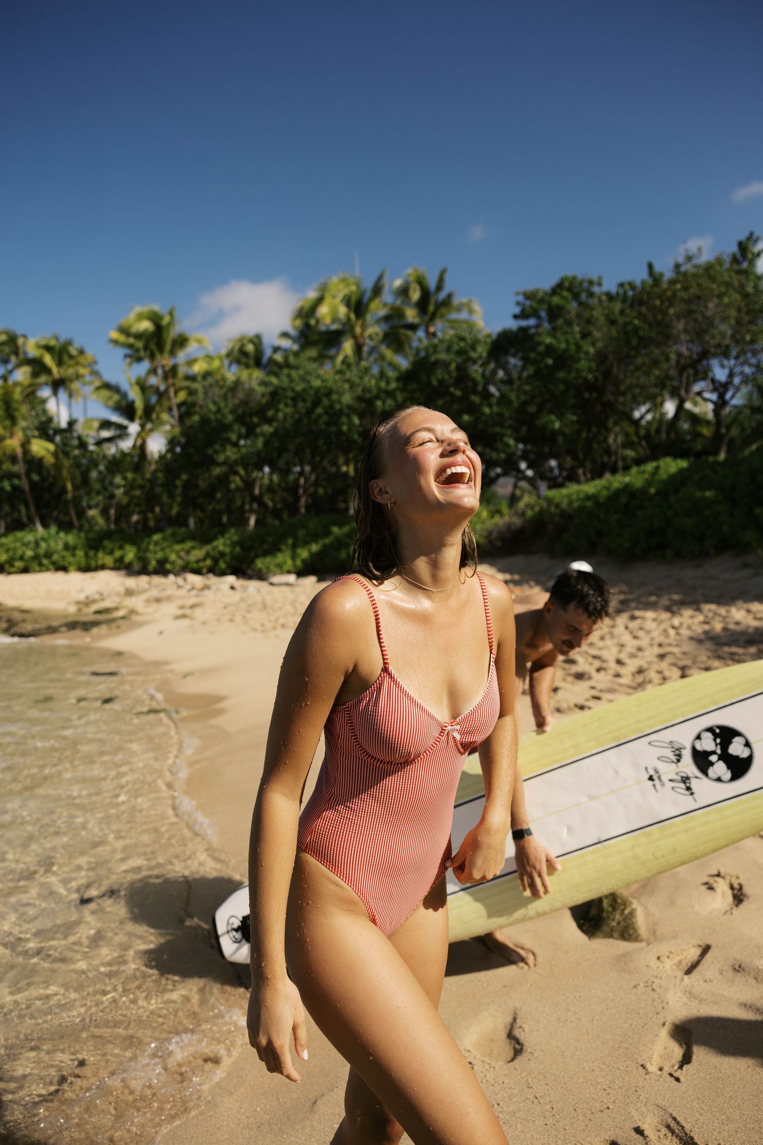 Beachgoers with surfboards enjoying a sunny day on a tropical sandy shore.