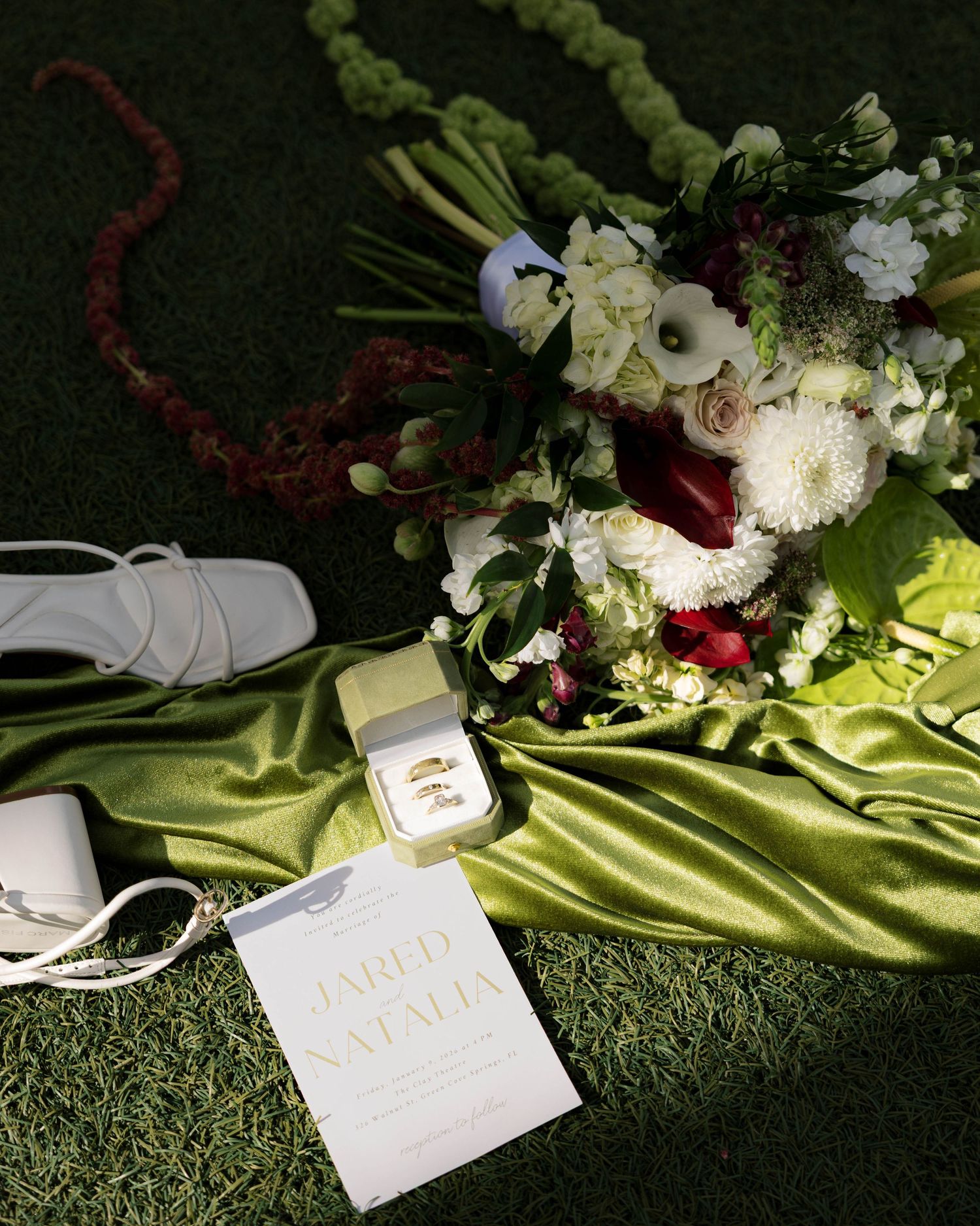 Lush floral arrangement with white flowers and red accents on chartreuse silk backdrop.