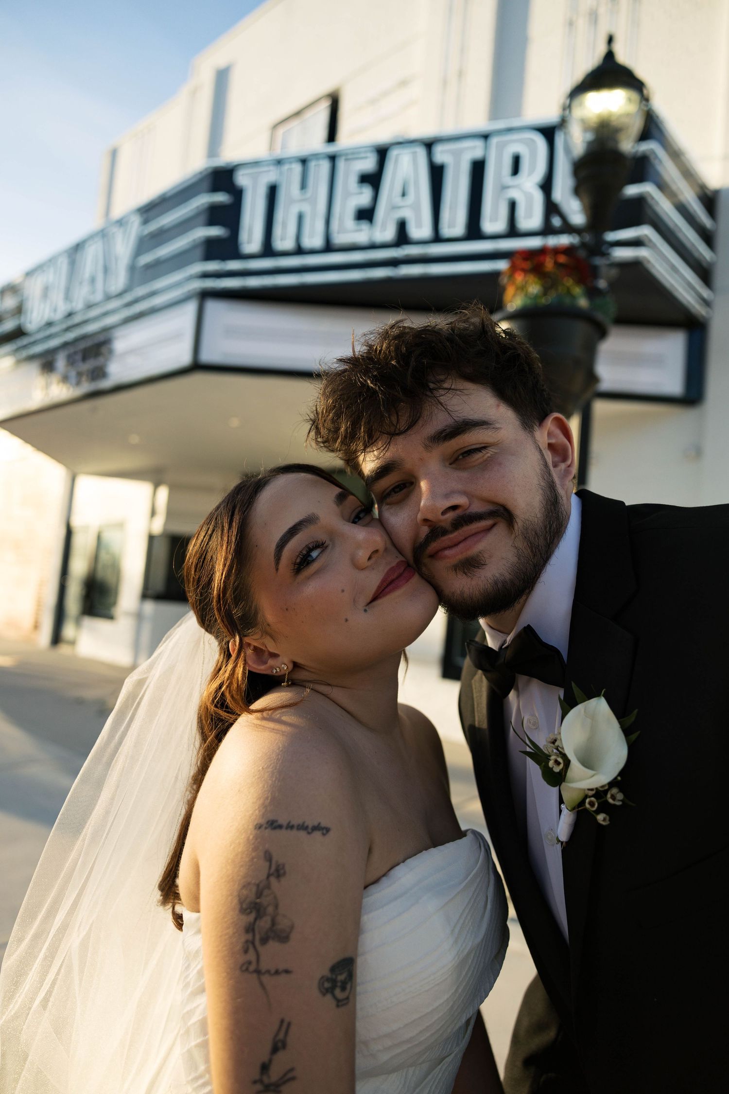 A tender wedding moment captured outside the historic Clay Theatre with golden sunlight.