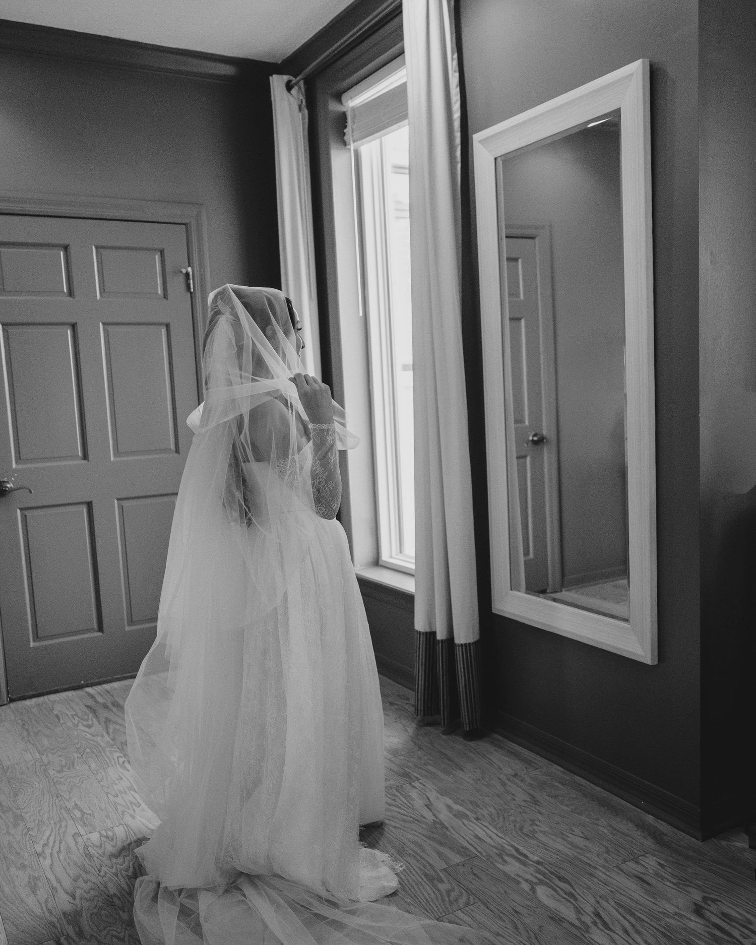 Series of wedding dress shots hanging in an elegant hallway with white doors.