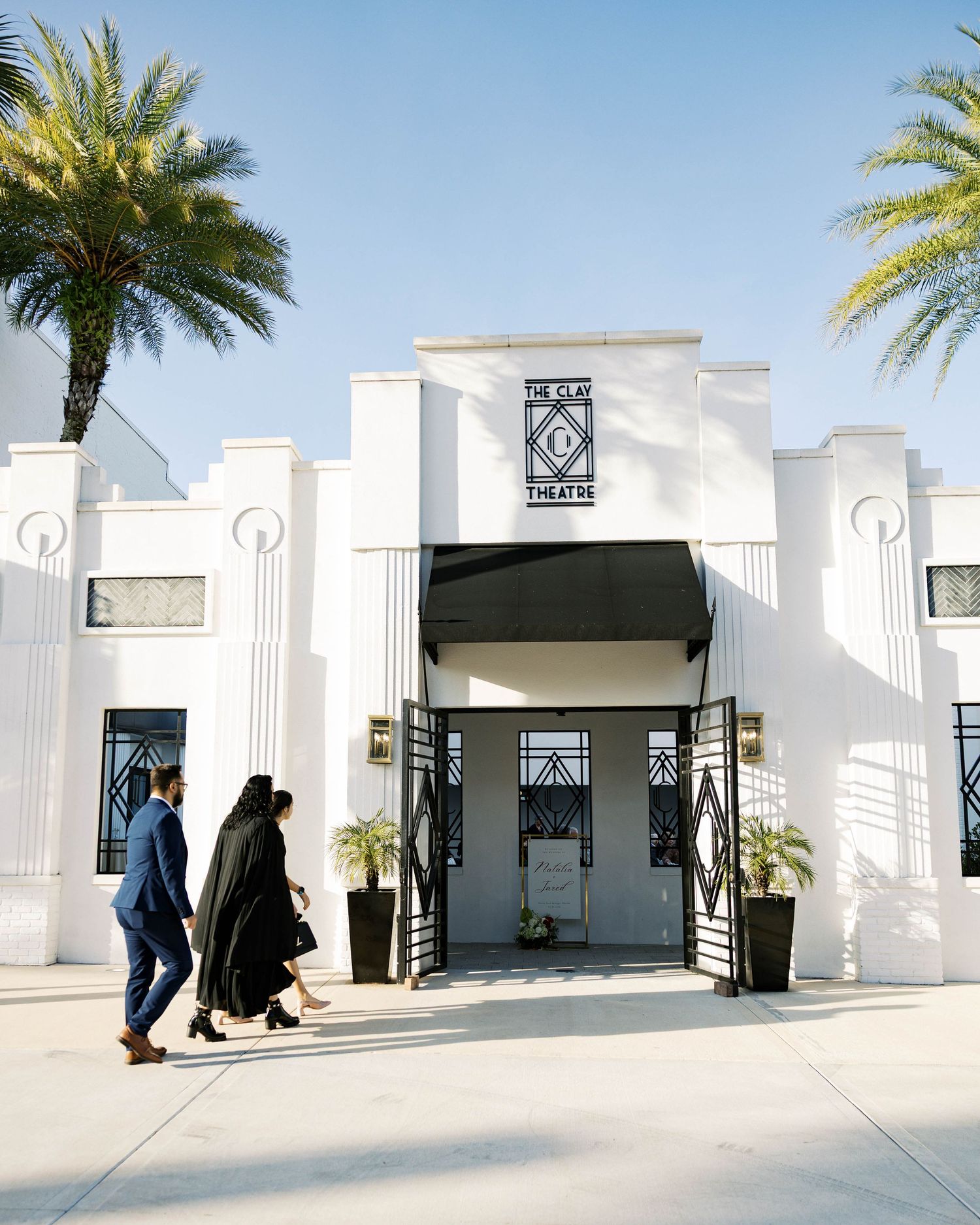 Modern white event venue exterior with palm trees and art deco architectural details.