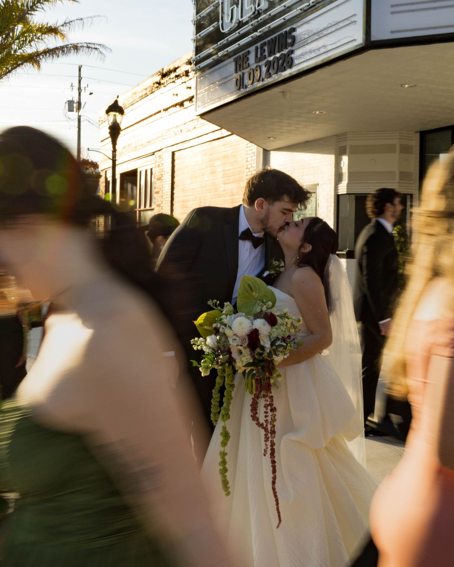 Motion-blurred candid shots of wedding party members outside theater entrance at sunset.