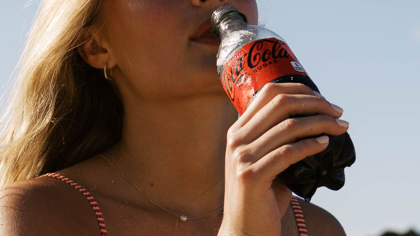Close-up shots showing someone enjoying a cold Coca-Cola drink at the beach.