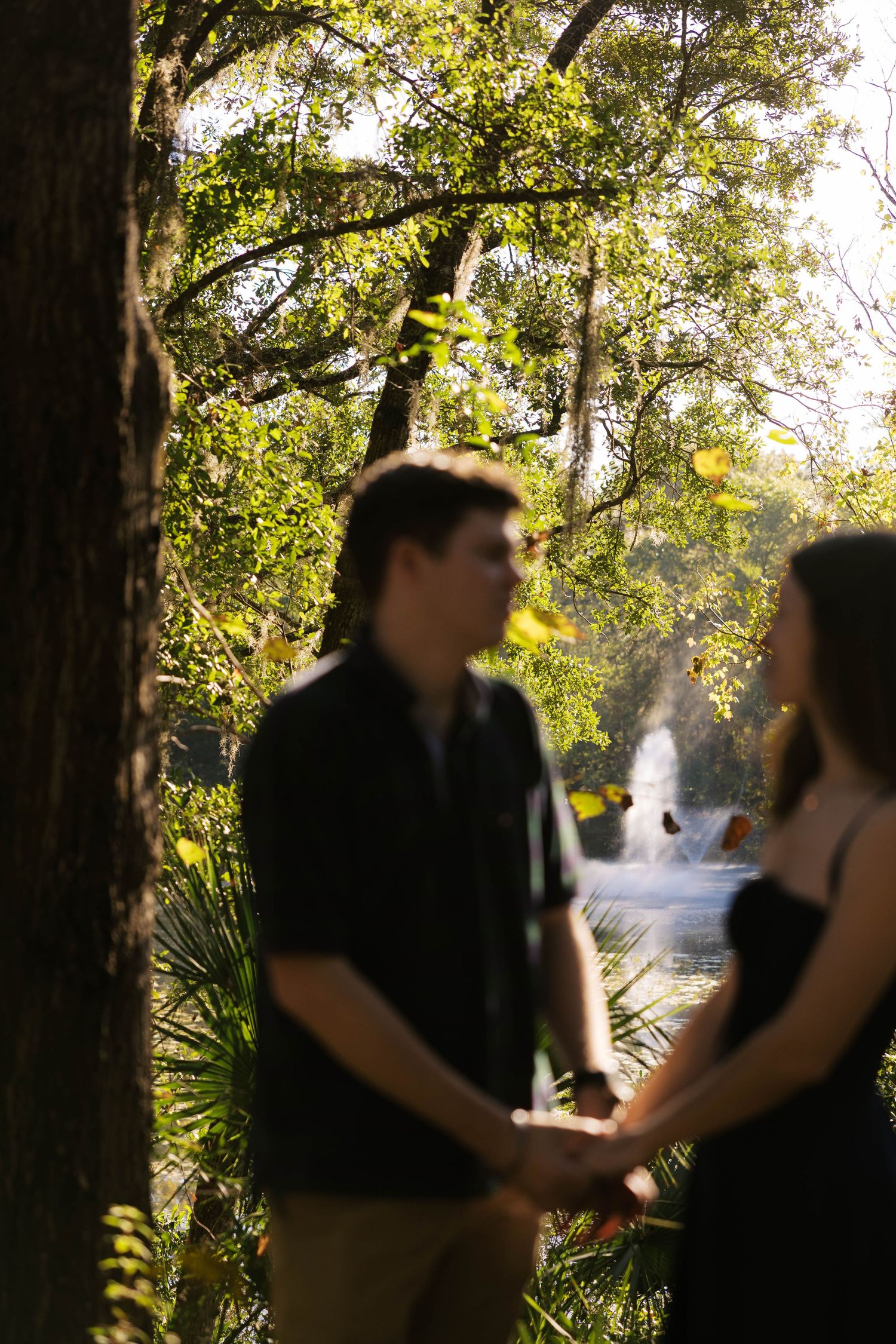 Romantic outdoor photoshoot in a sunlit wooded area with natural greenery.