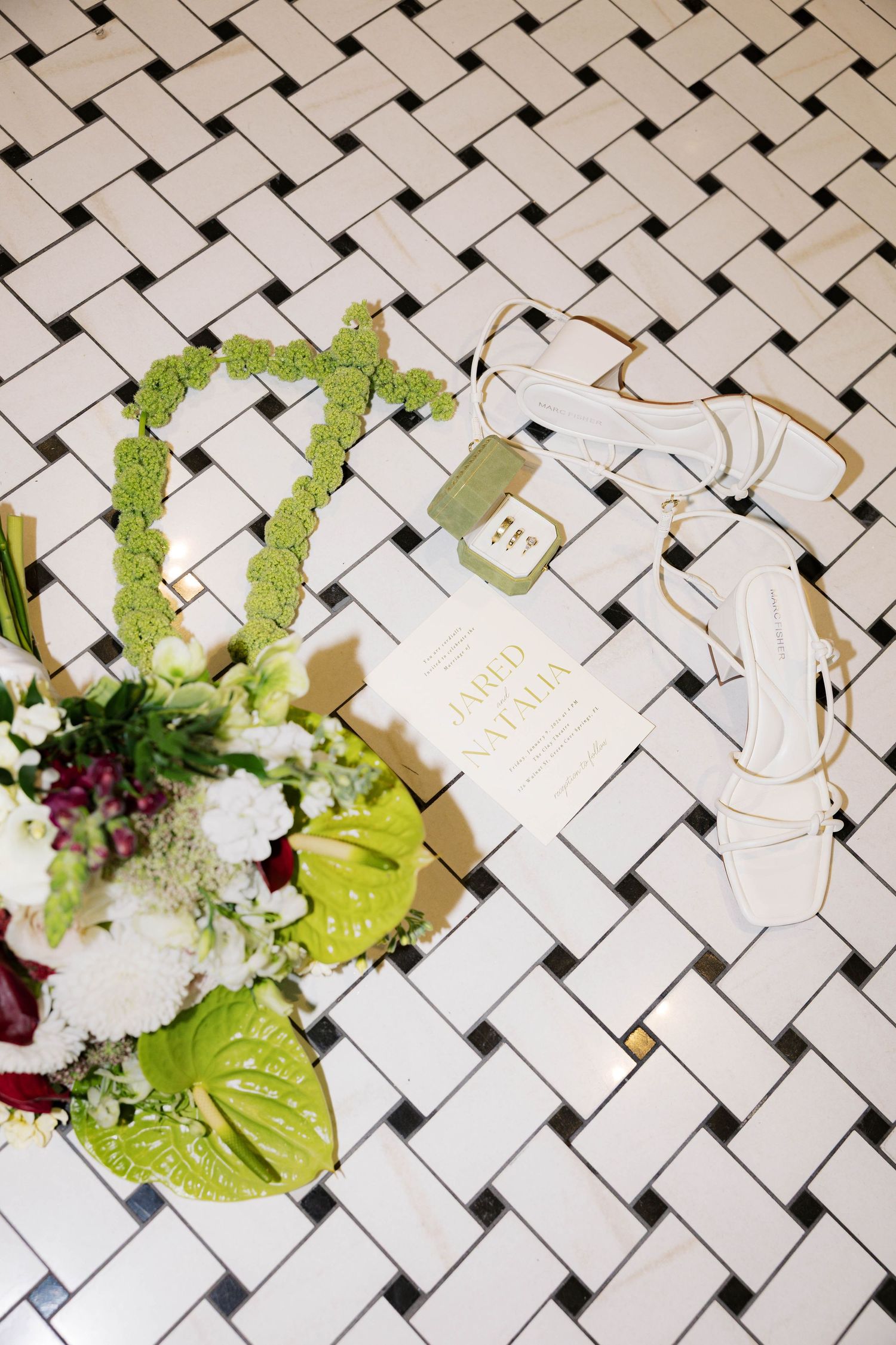 Overhead view of wedding florals and name cards arranged on white basketweave tile pattern.