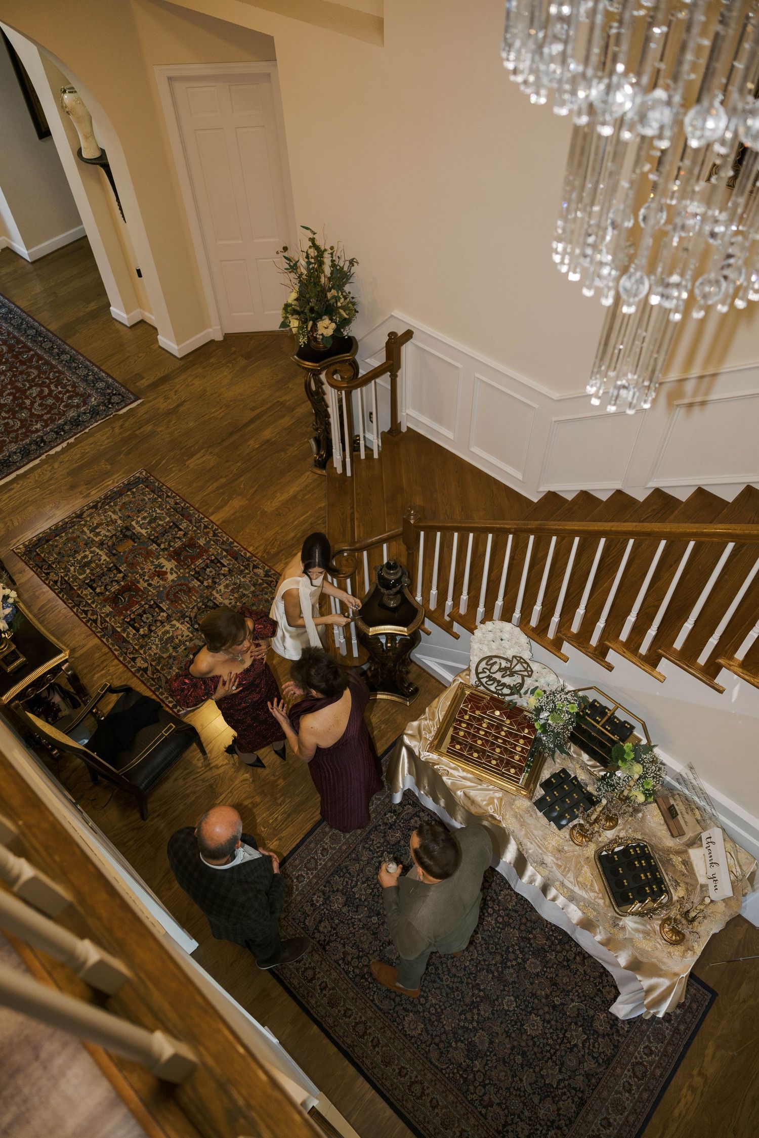 Overhead view of an elegant indoor gathering with a chandelier and staircase.